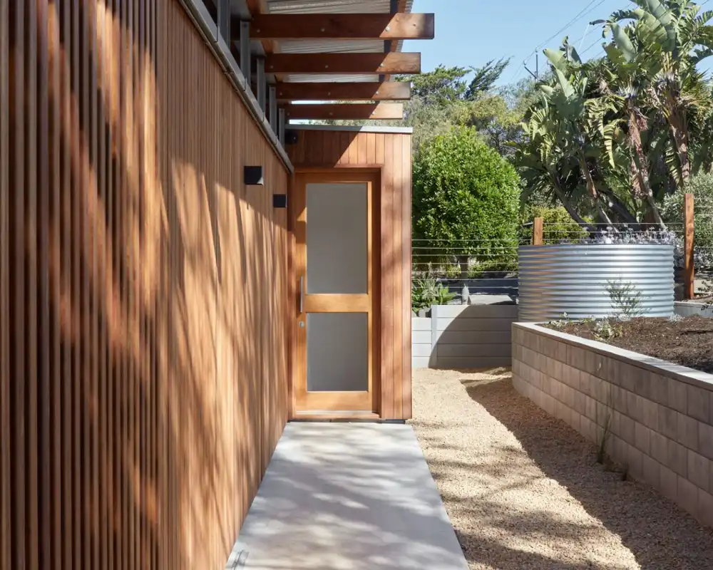 Sunlit timber cladding and entry door of Sydney home protected with weatherproof exterior coating.
